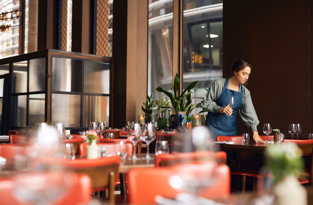 Waitress sets a table in a restaurant before opening.